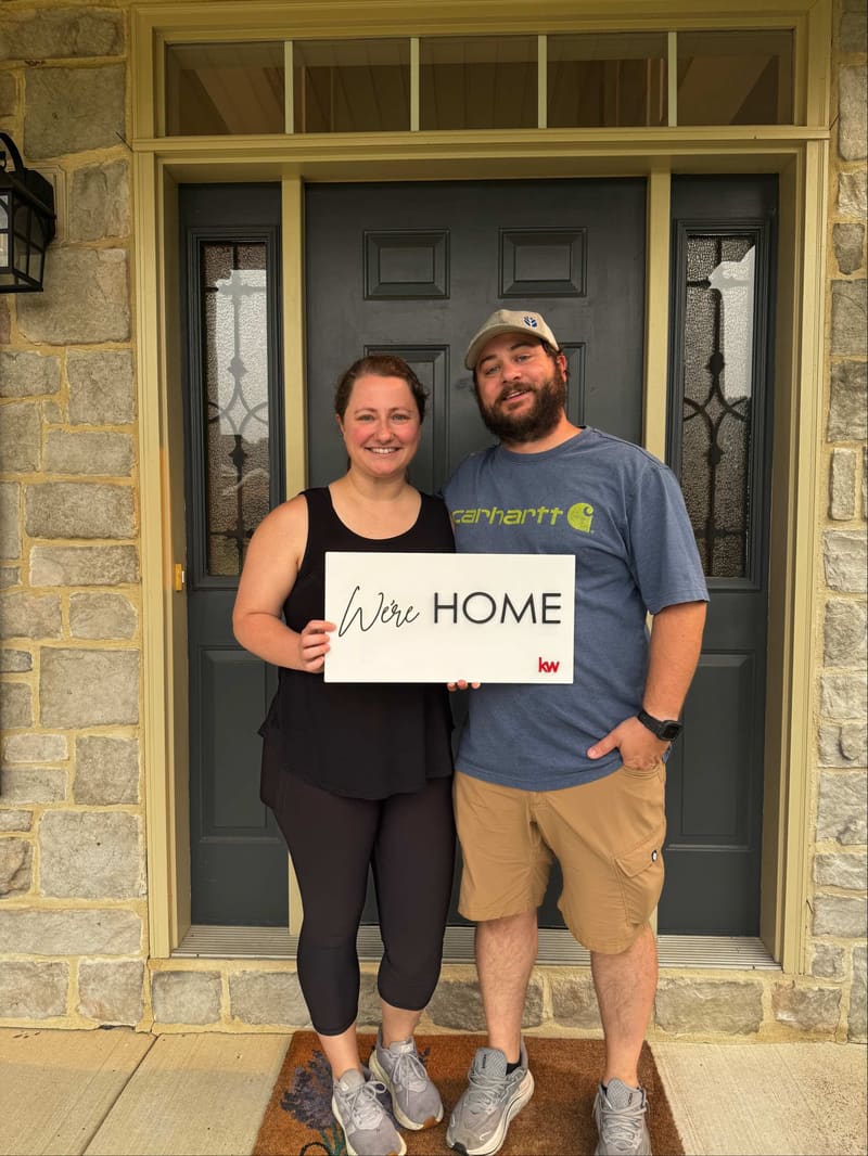 Shelby and Jordan holding their We’re Home sign at their new Hummelstown home