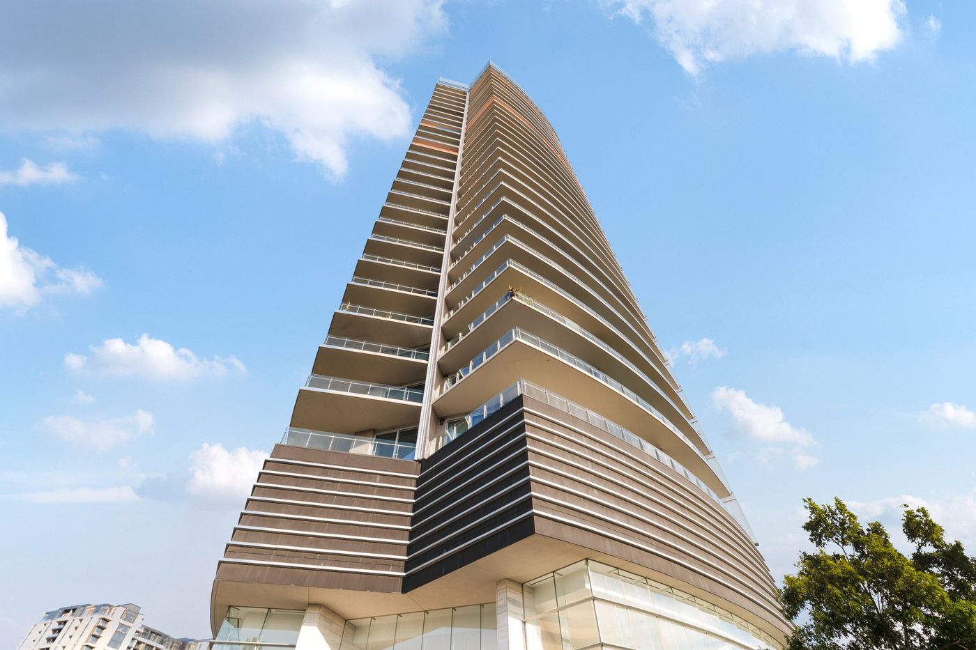 Looking up at the curved glass facade of the Bleu Ciel tower in Dallas