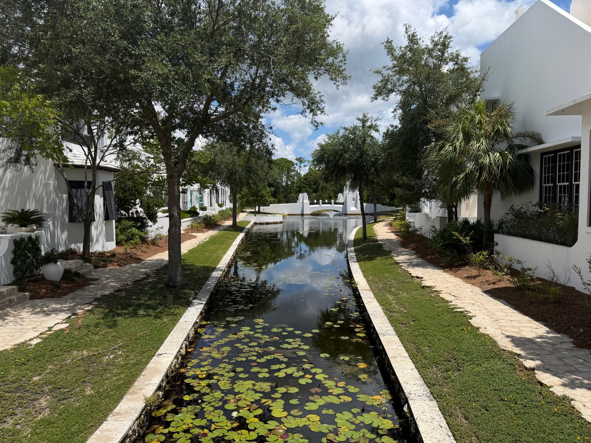 Reflecting water feature between landscaped walkways and white homes in Alys Beach