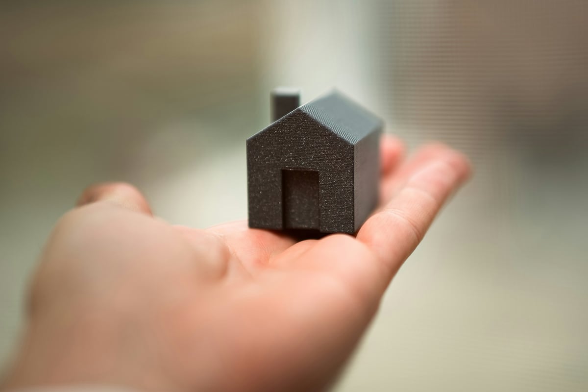 A small model house held in an open hand