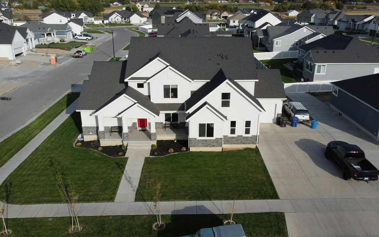 Aerial view of a white two-story house with a red front door and broad lawn.