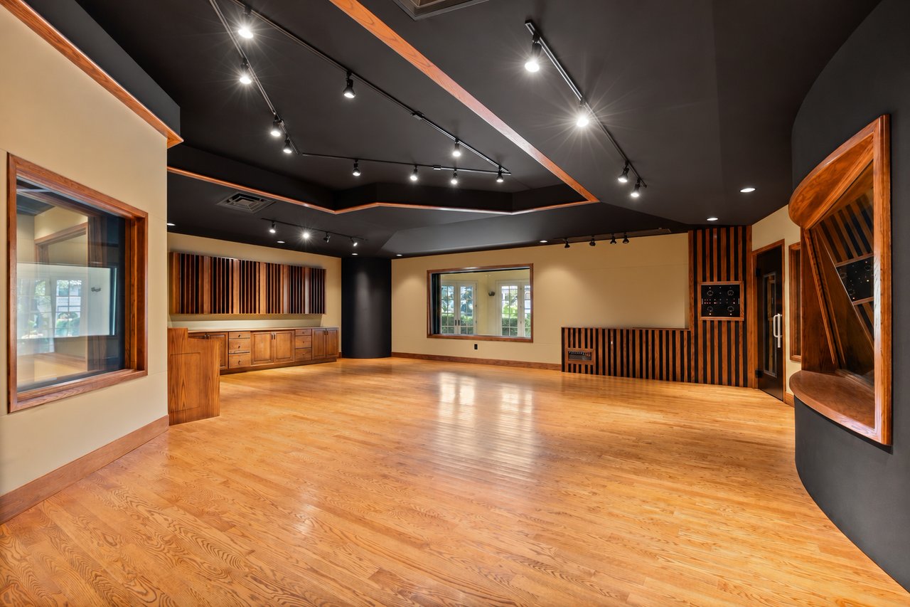 Media room with polished wood floors, acoustic wood slats, and a dark track-lit ceiling.