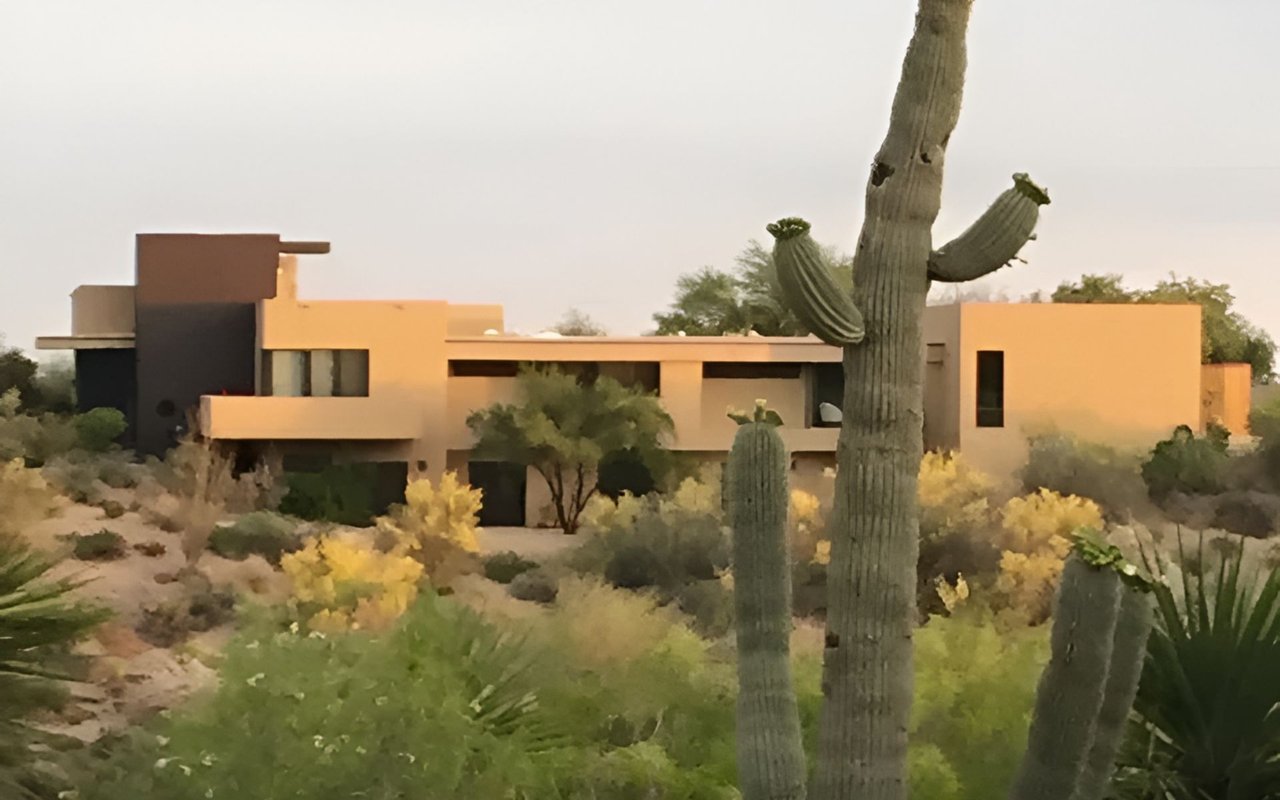 Modern desert home framed by tall saguaro cacti and desert landscaping.
