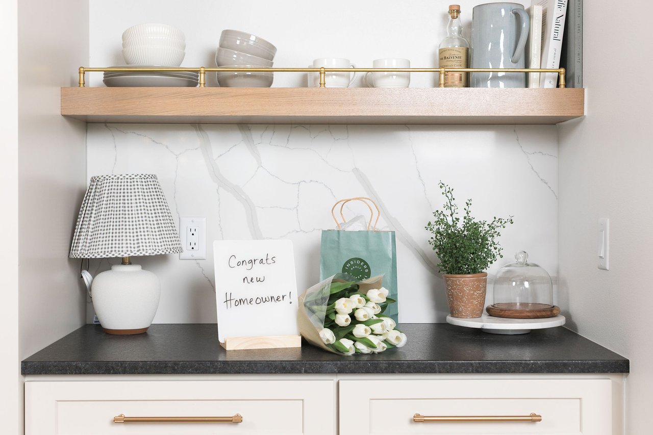 A welcoming kitchen counter featuring a "Congrats new Homeowner!" sign and an Insiders Realty gift bag, representing the rewarding finish line for buyers navigating the true cost of homeownership in Verona.