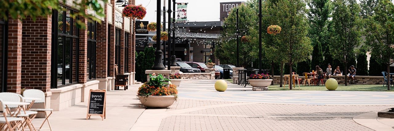 Downtown Hudsonville with brick storefronts, outdoor seating, and tree-lined streets.
