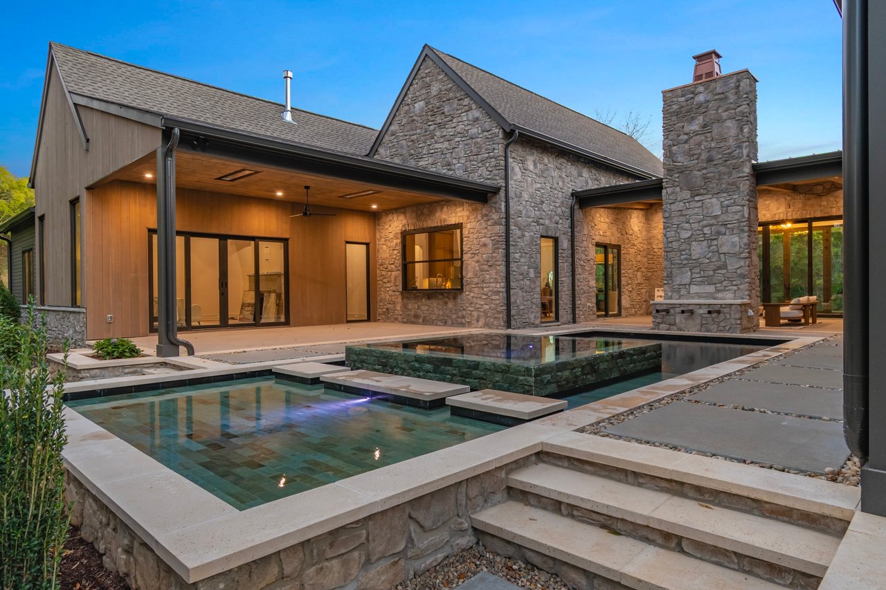 Stone-and-wood home with a covered patio and geometric swimming pool.