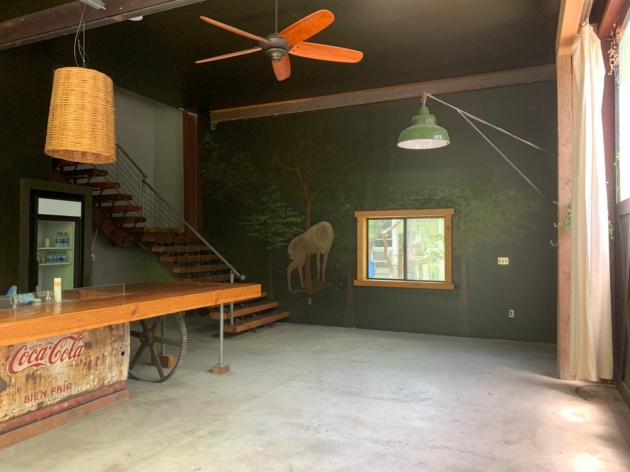 Main level with a painted forest mural, wood-top bar, and concrete floors at 640 Tillery Street, Govalle, East Austin.