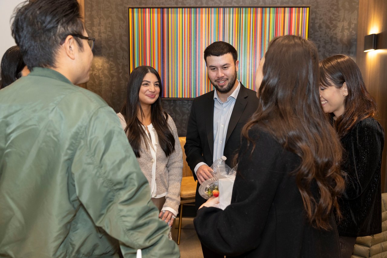 Guests mingle at an open house in front of colorful striped artwork.