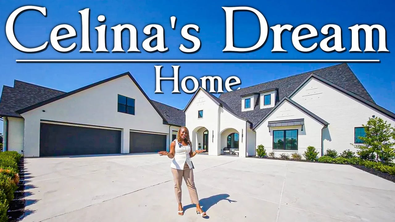 White luxury home with a three-car garage and a woman standing in the driveway.