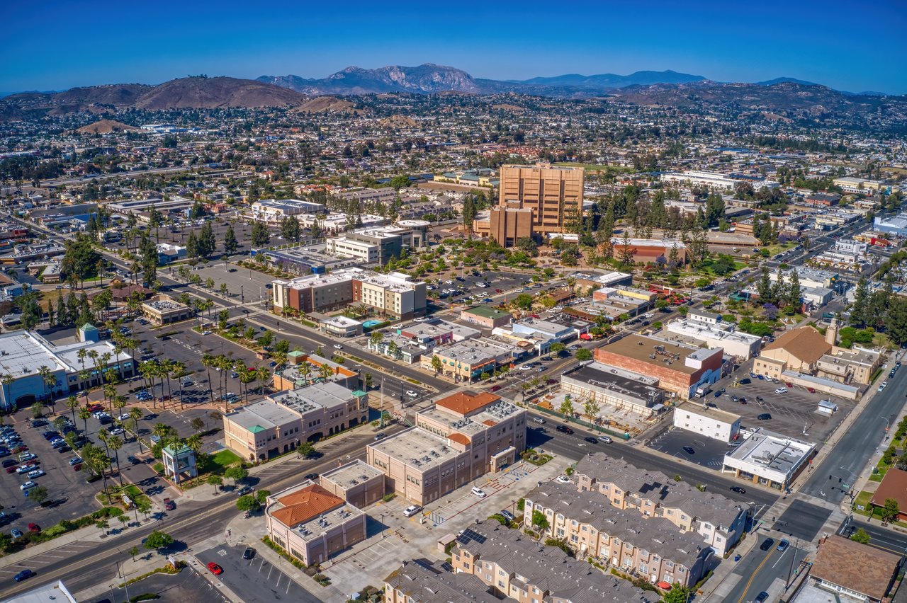 Aerial view of El Cajon’s commercial district and neighborhoods, with hills and mountains in the distance.