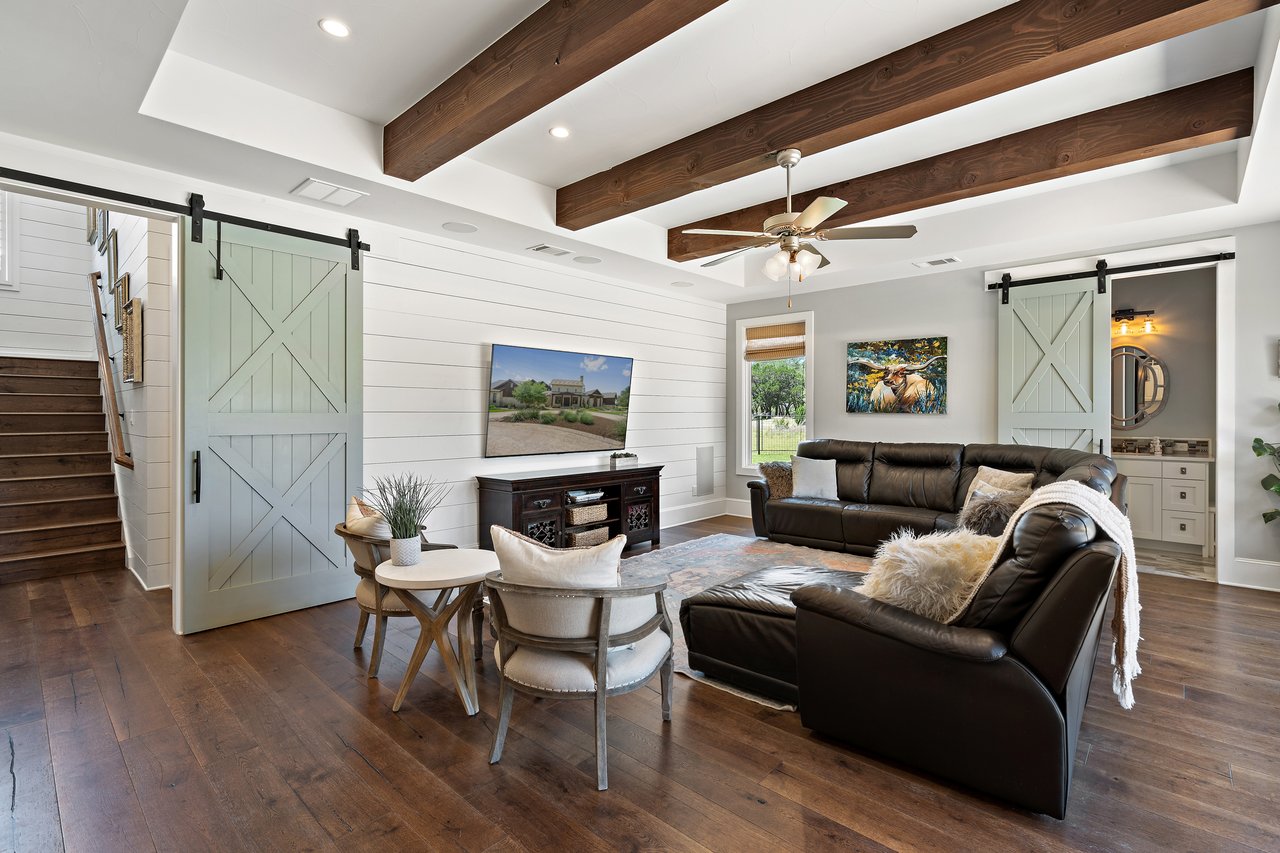 Family room at 335 Winning Colors featuring sliding barn doors and a television, with warm wood flooring throughout.