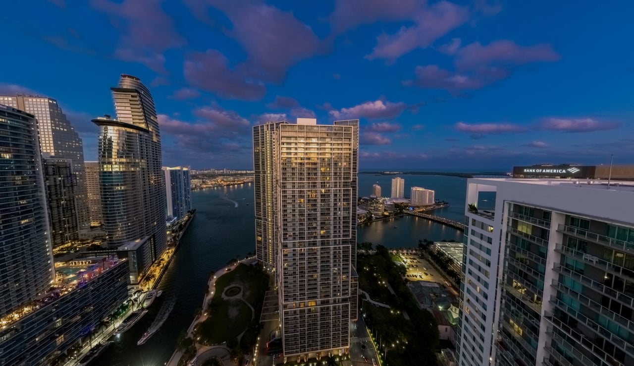 Aerial view of Brickell high-rises and waterways at dusk, with a residential tower centered.