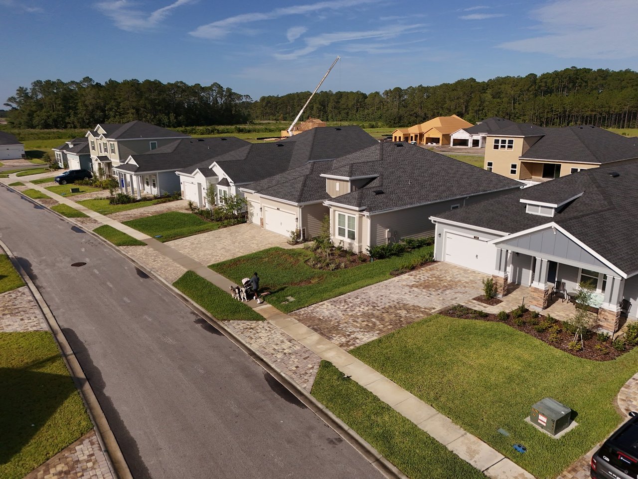 Aerial view of newly built Silver Falls homes along a residential street, with a construction crane in the background.