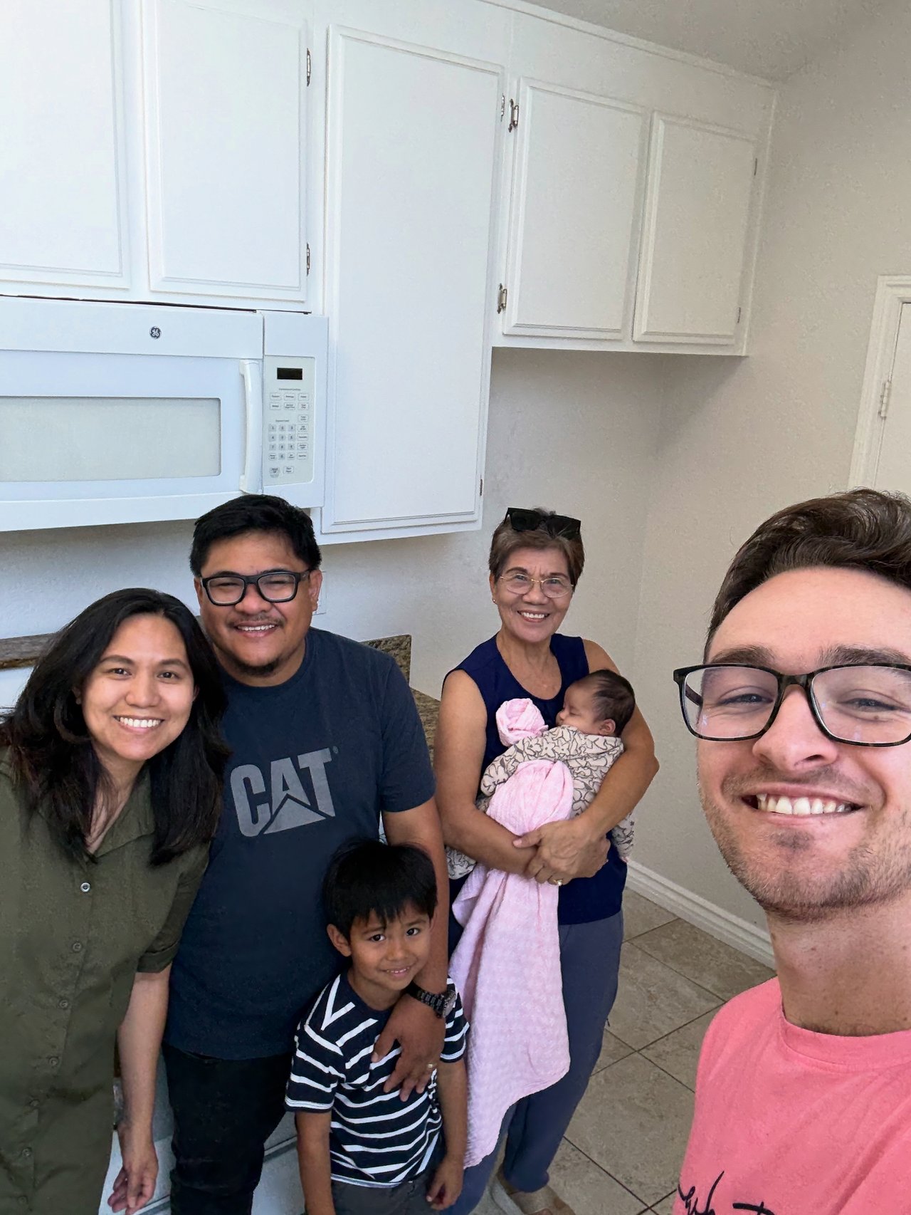 Family with a baby and their real estate agent pose together in a kitchen.