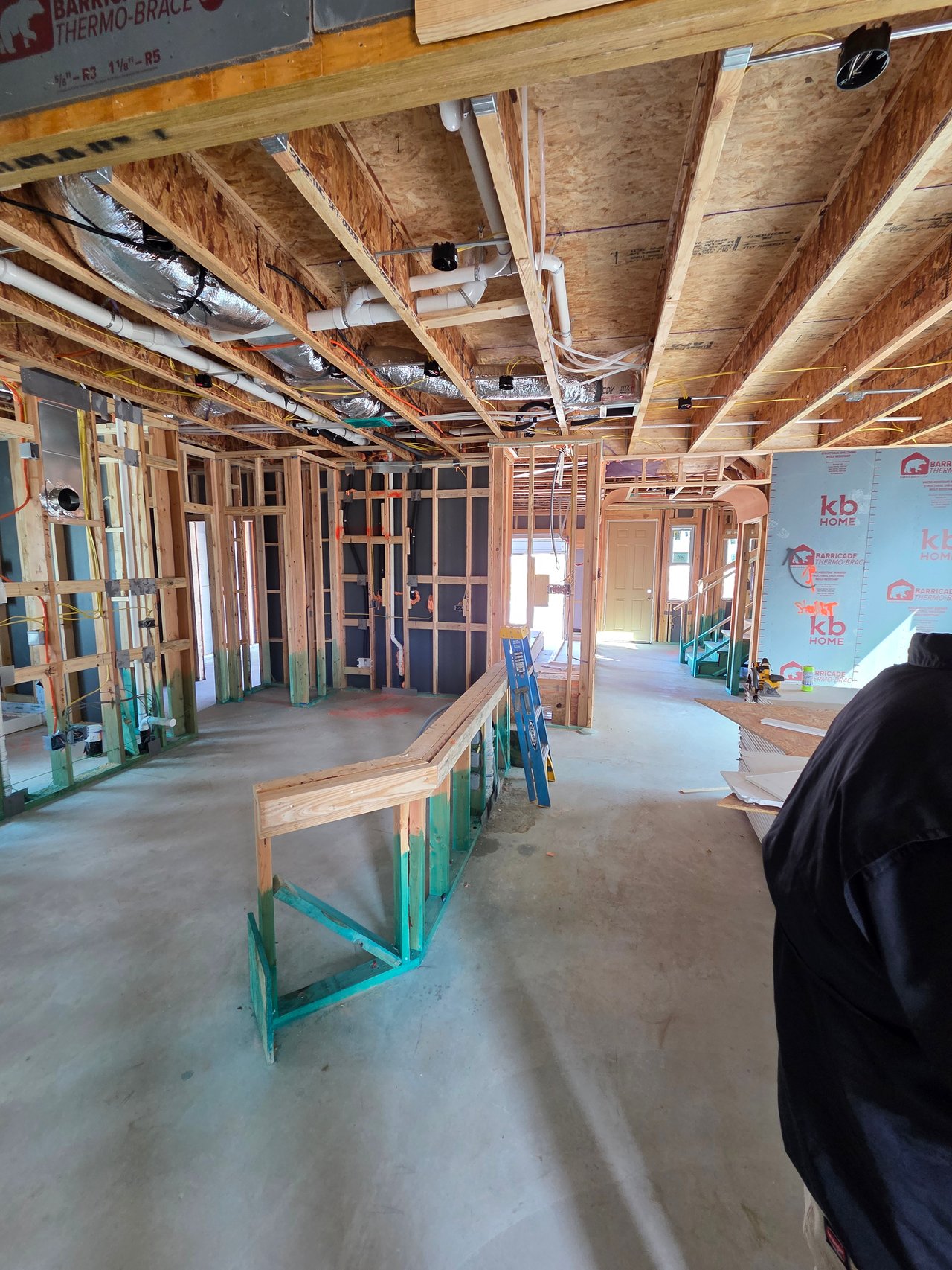 Unfinished home interior with exposed framing, ceiling ductwork, and a blue ladder.