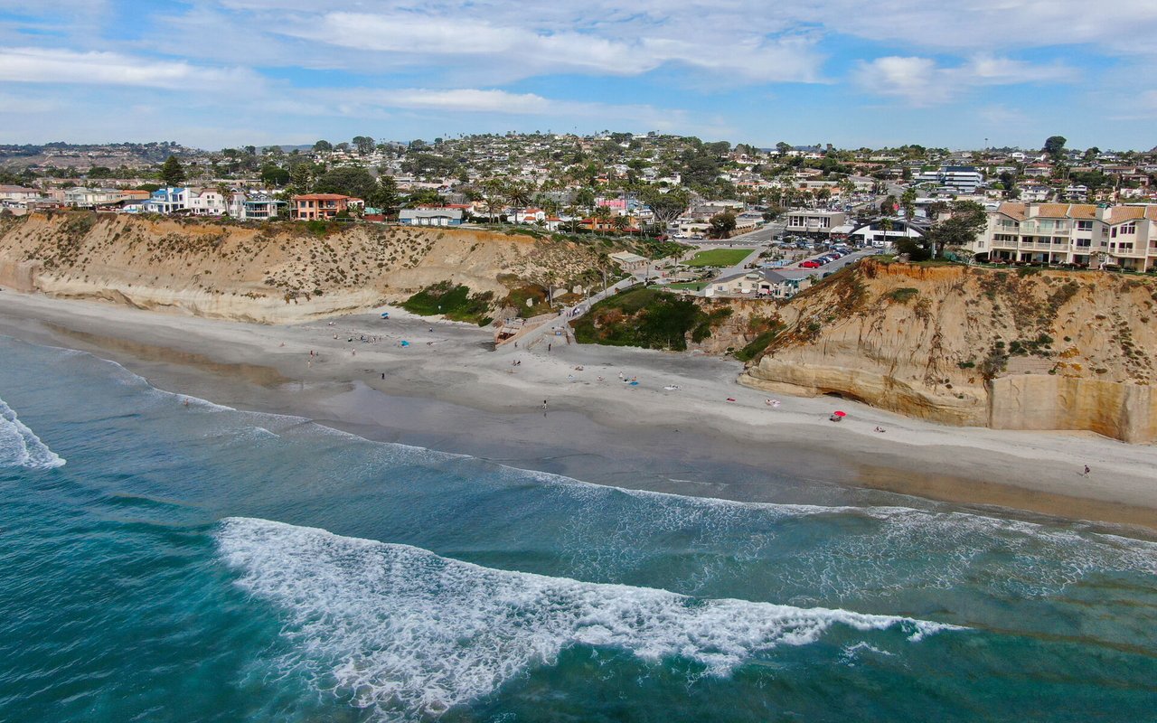 Solana Beach coastline with sandy shore, ocean waves, coastal bluffs, and homes above.