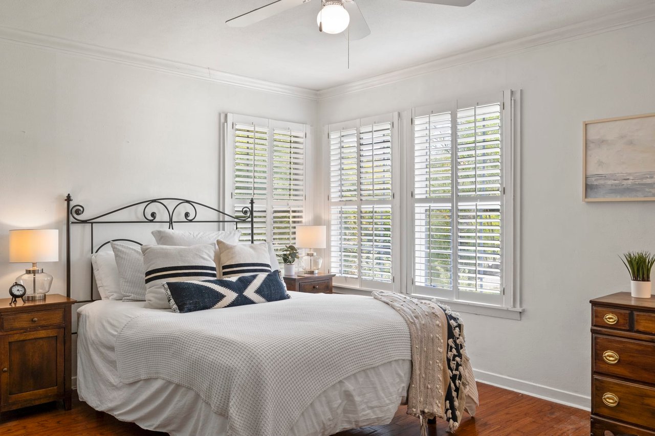 Bedroom with original wood floors and plantation shutters in this Tarrytown, Austin home.