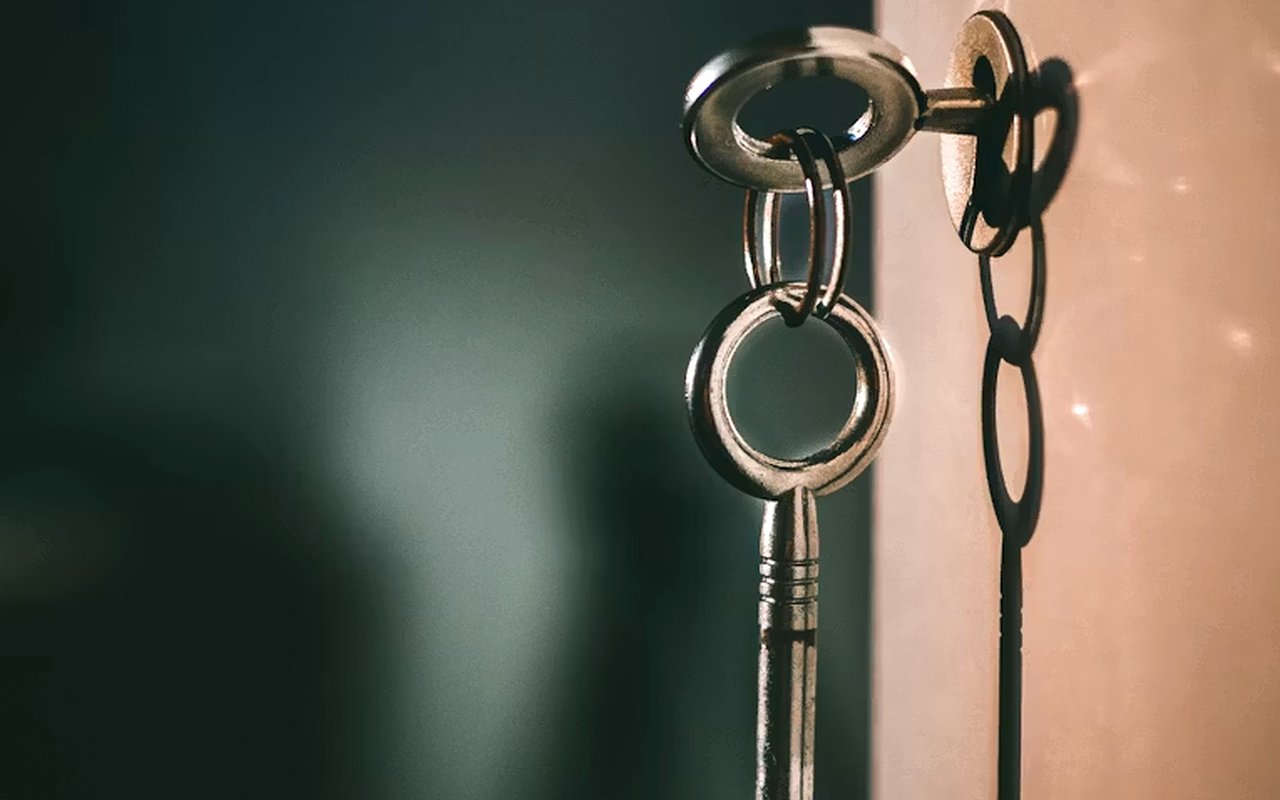 Metal keys hanging from a lock against a softly blurred background.