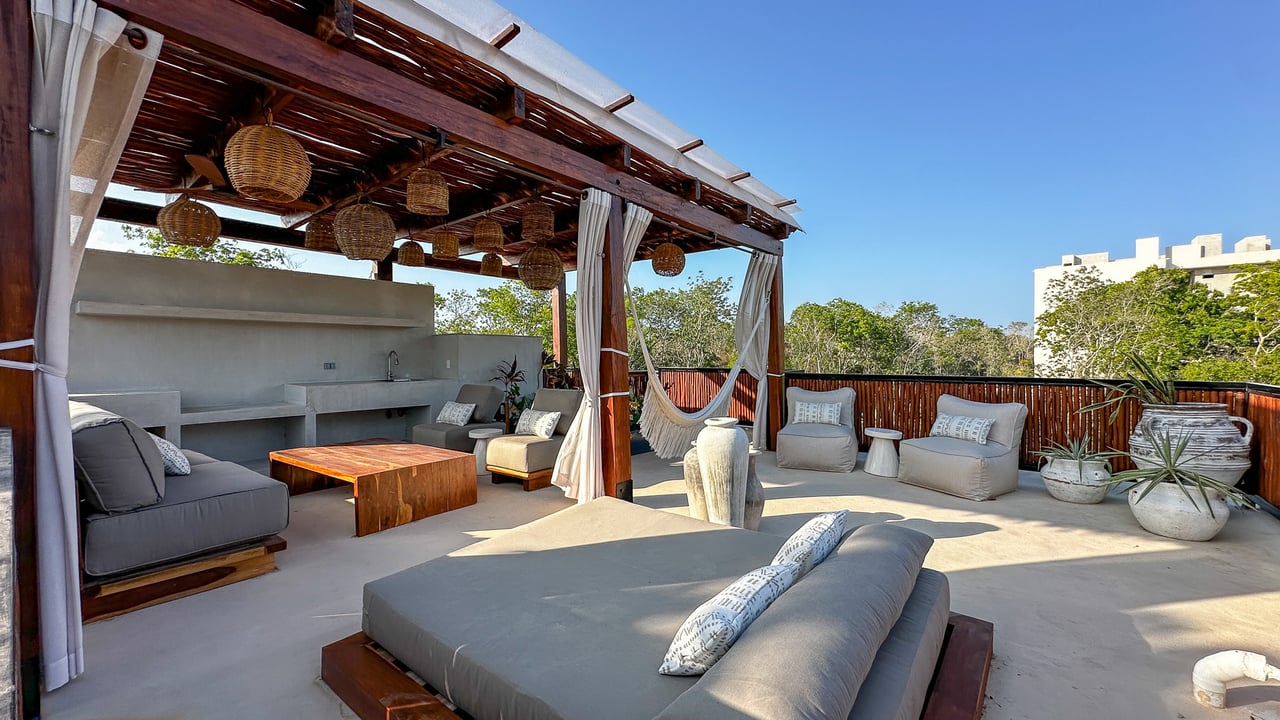 Rooftop terrace with a timber pergola, outdoor kitchen, hammock, and cushioned lounge seating.