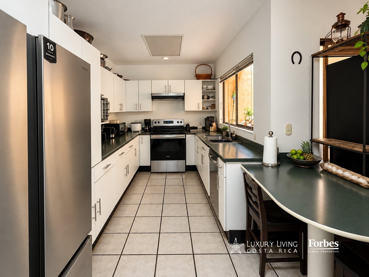 Kitchen with white cabinets, dark countertops, stainless steel appliances, and a window above the sink.