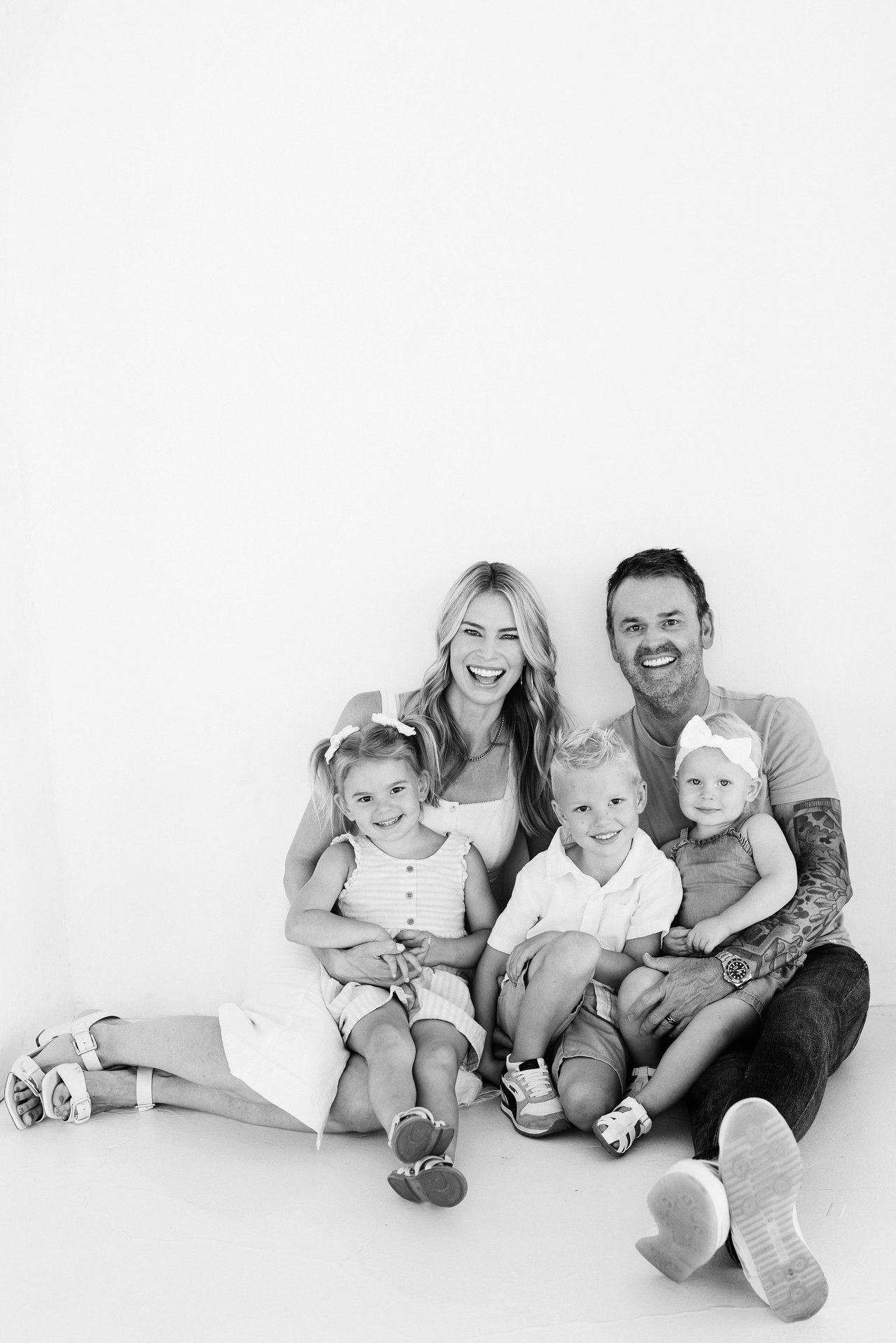 Two adults and three young children seated together in a smiling family portrait.