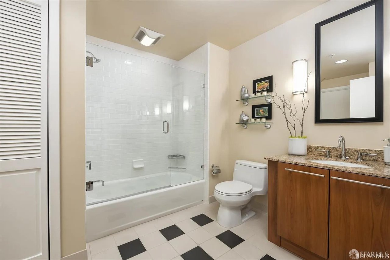 Bathroom with bathtub, wood vanity, and large mirror