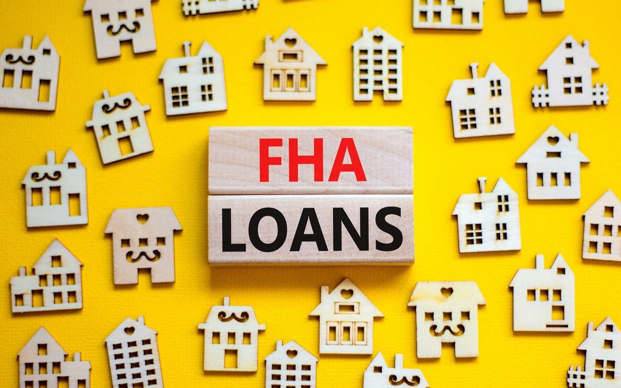 FHA loans blocks surrounded by wooden house cutouts on a yellow background.