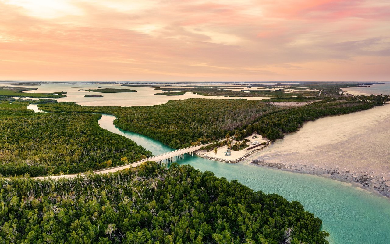 Aerial view of Sugarloaf Key mangroves and waterways, with a bridge crossing a turquoise channel at sunset.