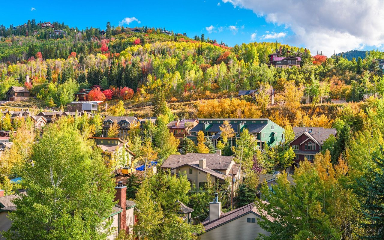 Hillside neighborhood homes surrounded by colorful autumn trees.