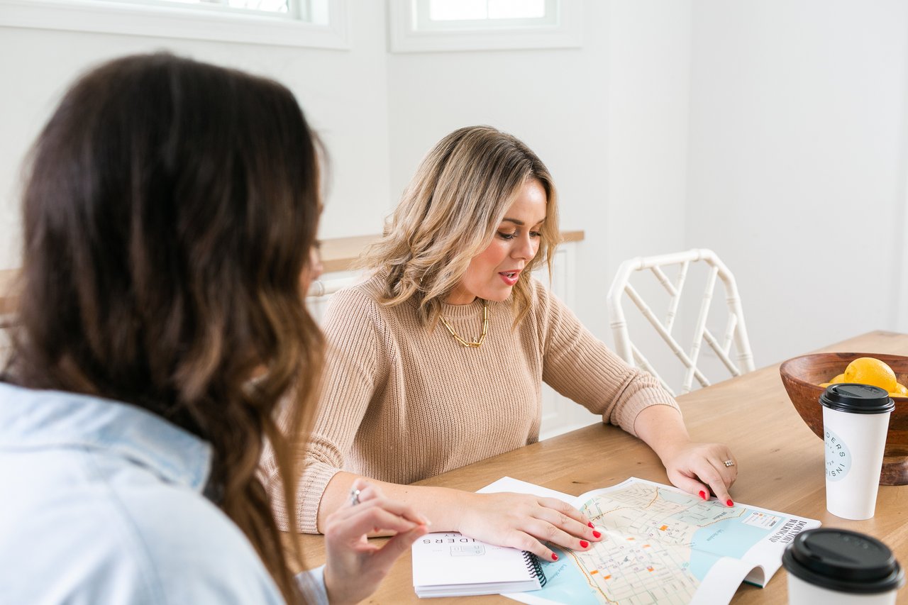 A buyer and an Insiders Realty agent reviewing a map and strategizing over coffee, illustrating the careful planning, local expertise, and clear communication required to win a competitive multiple-offer situation in Verona, WI.