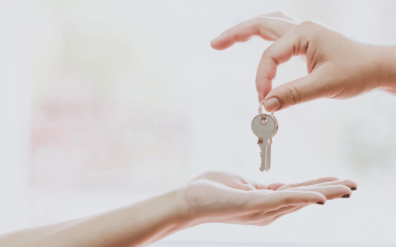 A hand passes a metal key to an open hand.