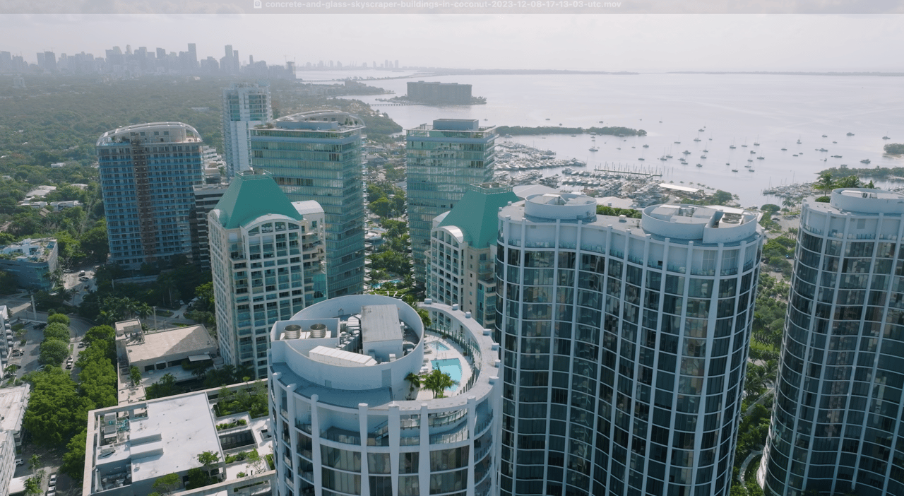 Coconut Grove high-rises beside a marina and Biscayne Bay, with the distant city skyline.