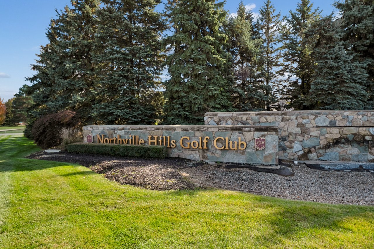 Stone entrance sign reading “Northville Hills Golf Club,” with evergreen trees behind it.