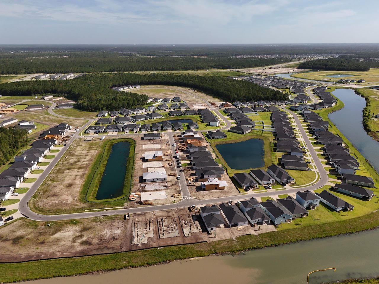 Aerial view of a subdivision with new homes, construction sites, and ponds.