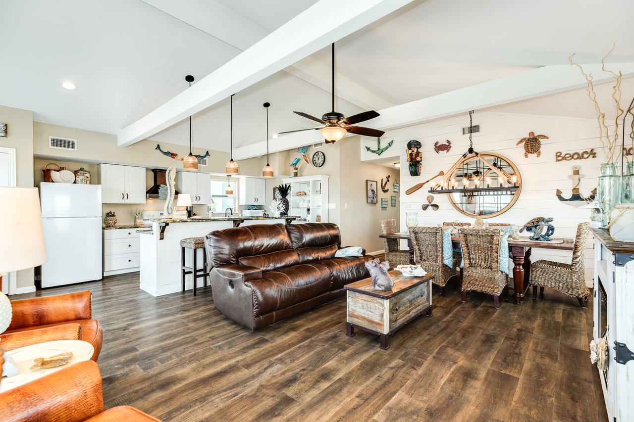 Interior photo of a large coastal home in Freeport, TX with open living space, multiple seating areas, and family-friendly layout perfect for entertaining with brown leather furnishings.
