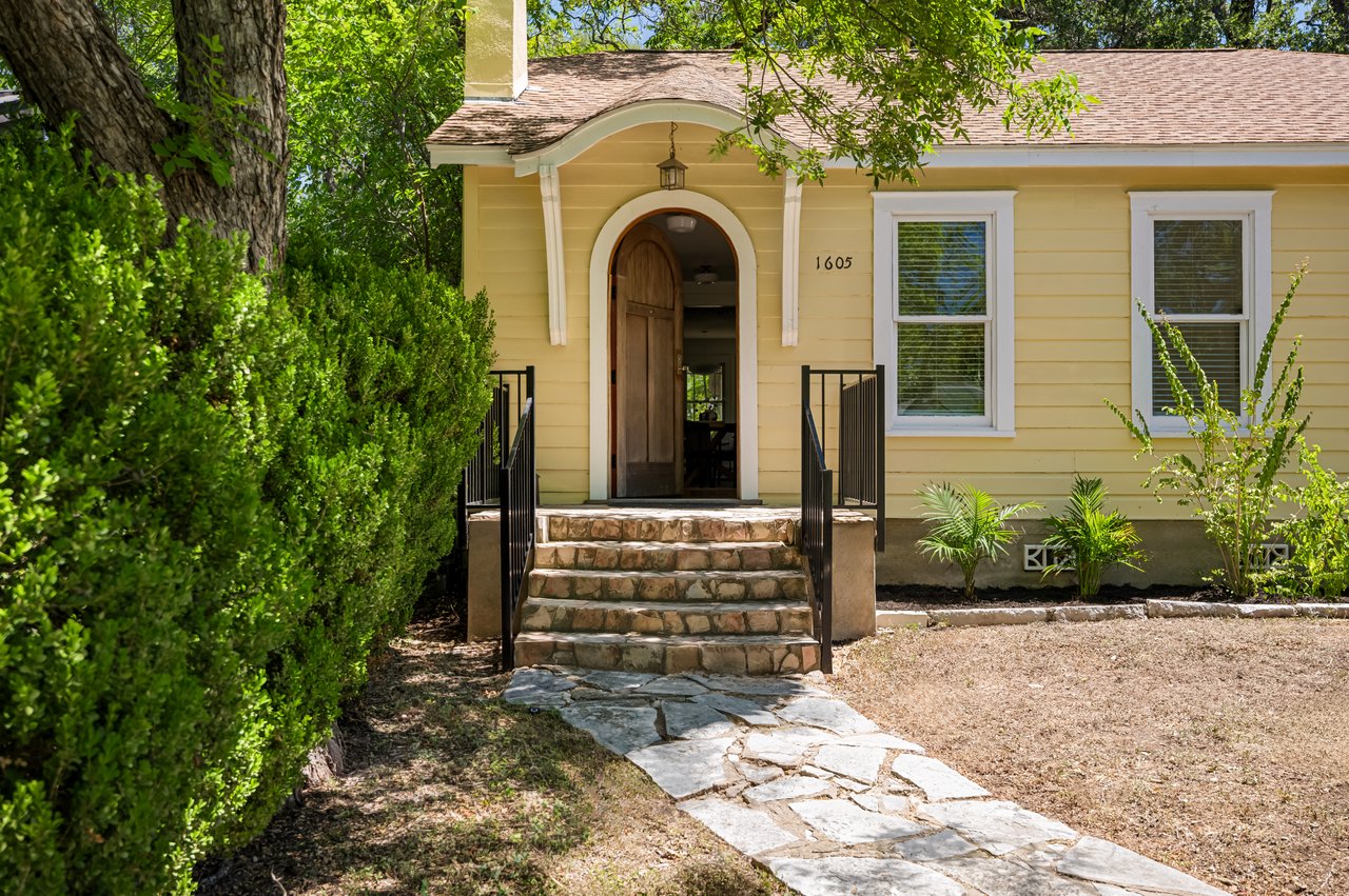 Yellow house with an arched entrance, stone steps, and a flagstone walkway.