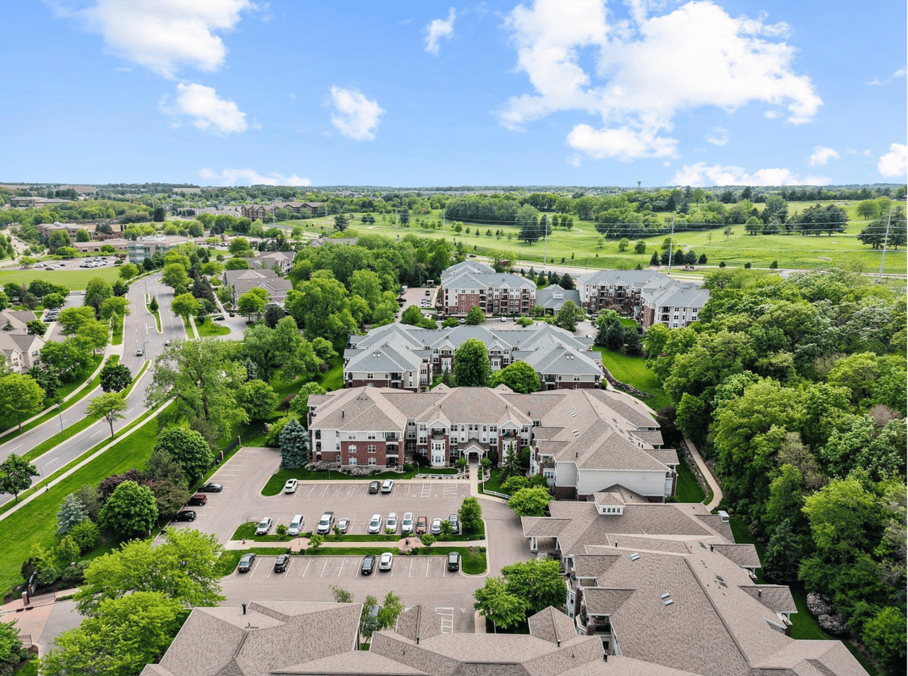 Aerial view of a sprawling condominium complex in Middleton, WI, representing the accessible under $400k real estate market, featuring well-maintained buildings nestled among mature trees and lush green spaces.