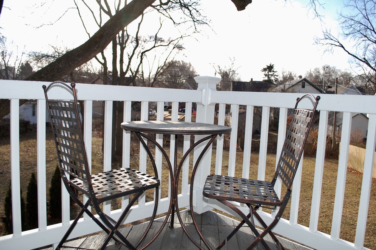 Deck with white railings and a metal bistro table and chairs overlooking a yard.