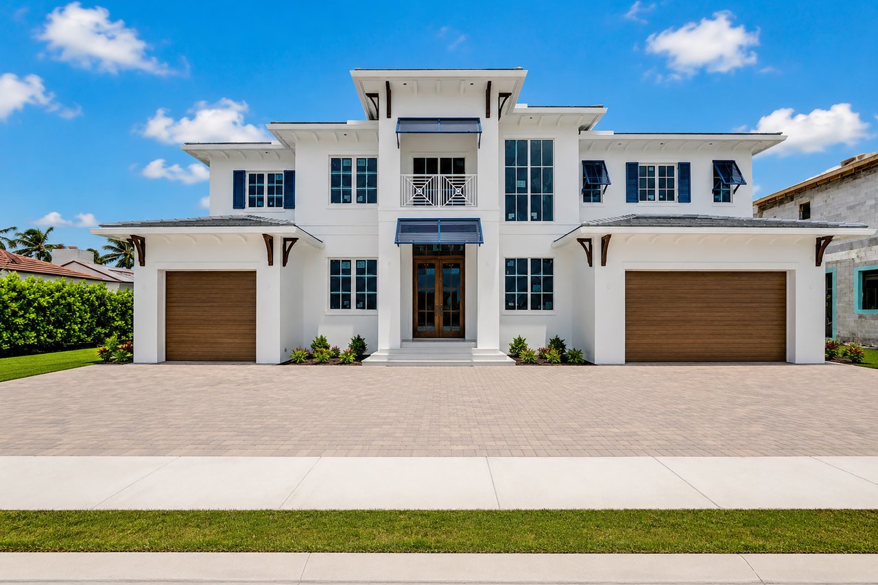 Two-story white home with dark-framed windows, twin garage doors, and a broad paved driveway.