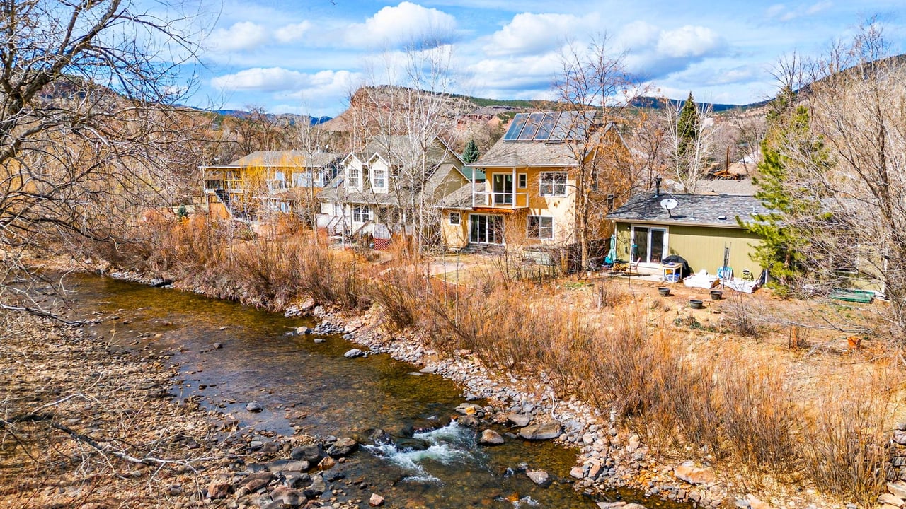 A serene riverfront home at 211 2nd Ave in Lyons, Colorado, sold by Kiki Kidder, featuring direct St. Vrain River access and lush foothills scenery.