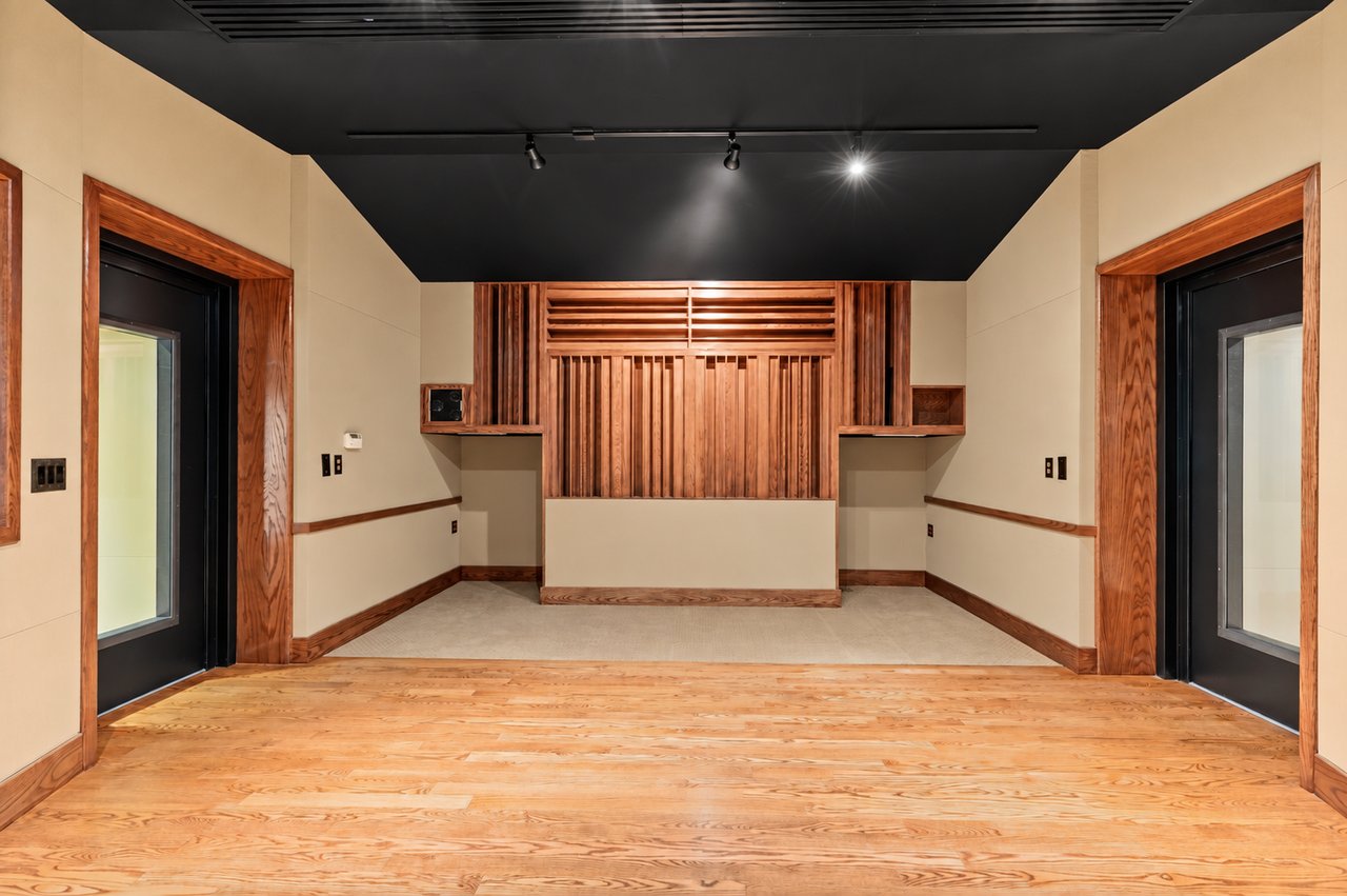 Empty media room with a wood-slat feature wall, black ceiling, and light wood flooring.