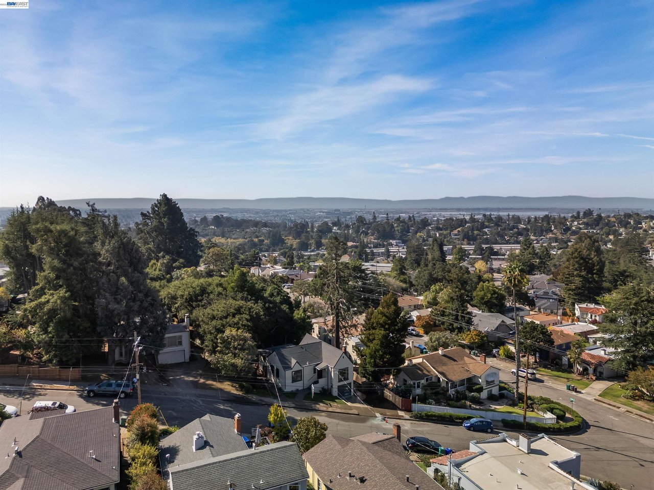 Panoramic Oakland neighborhood view with the bay and distant hills beyond the rooftops.