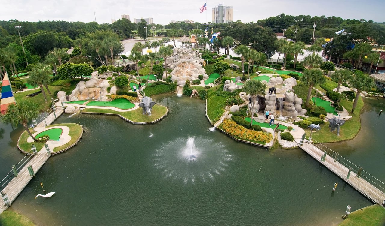 Miniature golf course with winding greens, rock features, and a fountain pond.