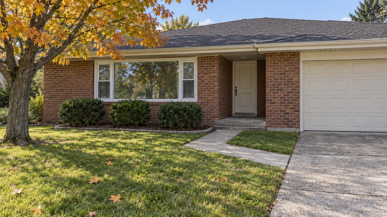 Brick ranch home with a recessed entry, broad white-framed window, autumn maple and a deep front lawn.