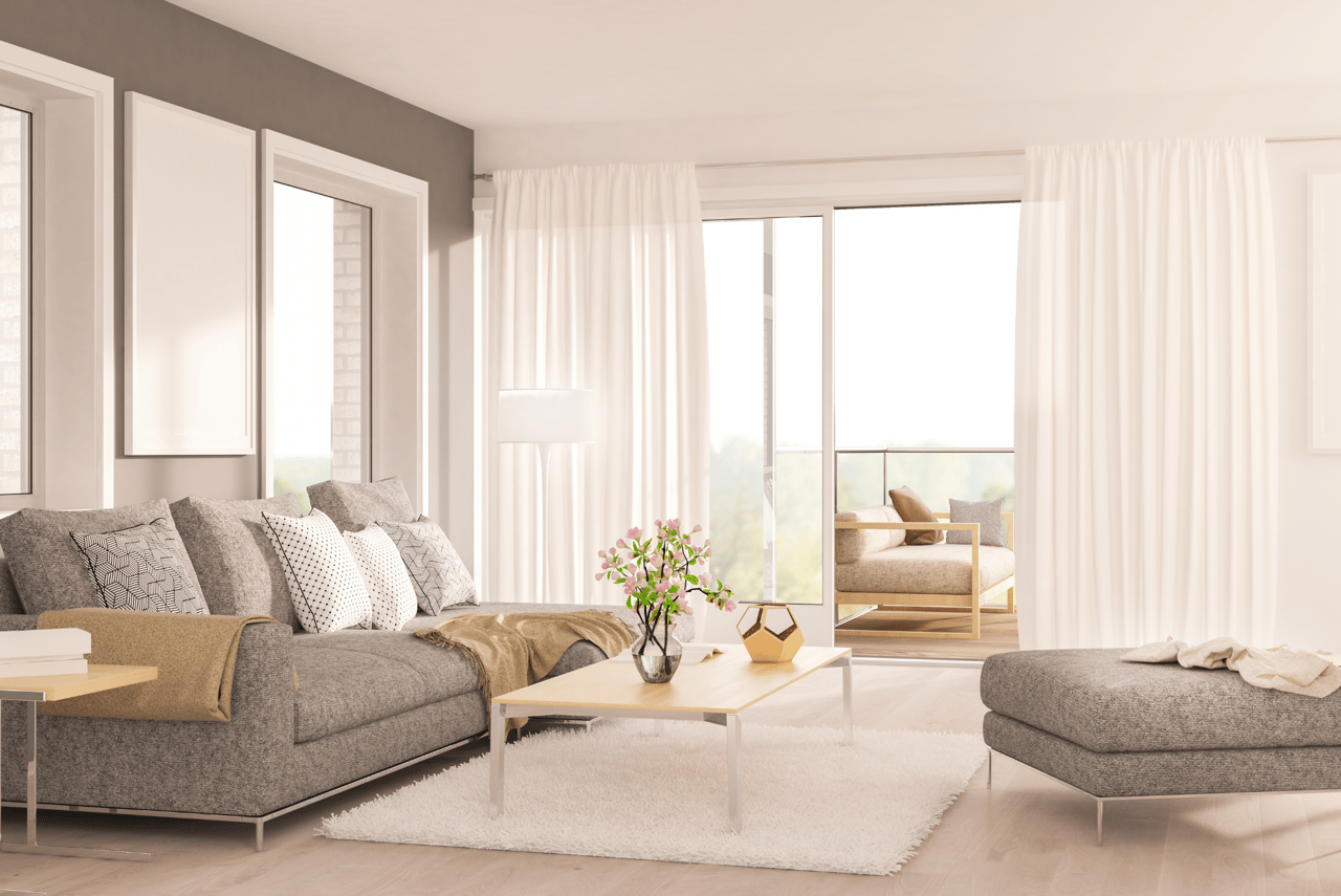 Bright living room with a gray sectional, light wood coffee table, and curtains framing sliding balcony doors.