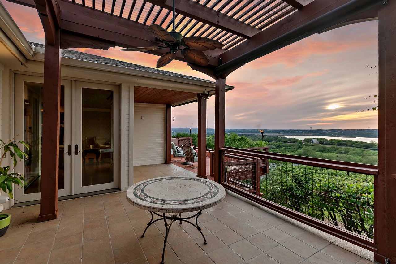 Covered patio under a wood pergola with an outdoor dining table and twilight Lake Travis views at 12709 Cedar St, Austin, TX 78732.