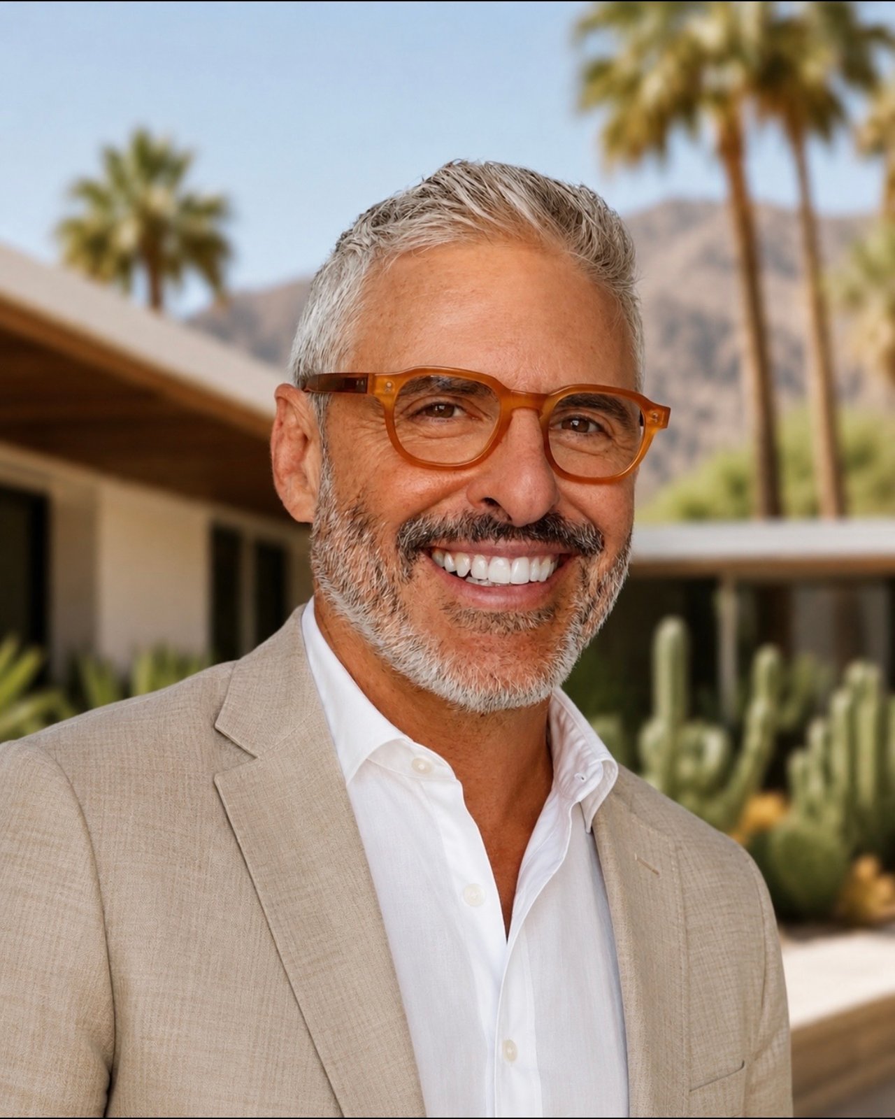 Mario Guariso wearing amber glasses and a beige blazer outdoors.