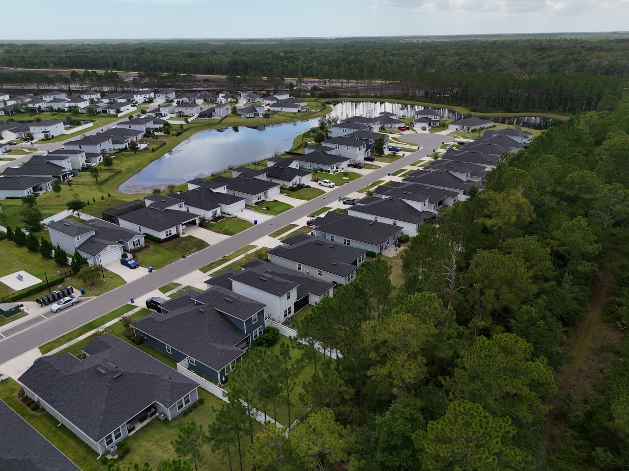 Aerial view of homes beside neighborhood ponds and dense woodland.