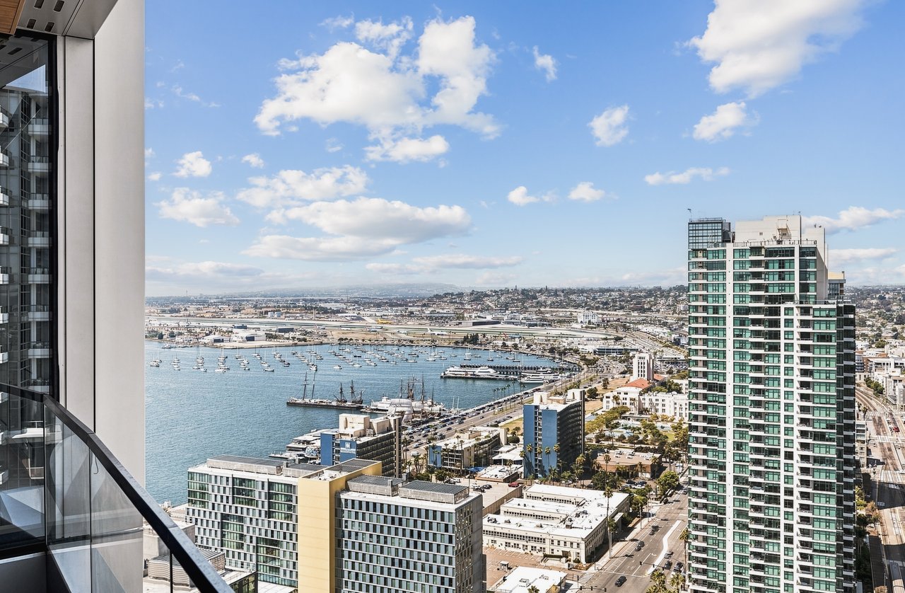 Harbor and downtown view from a high-rise balcony, with sailboats and neighboring towers.