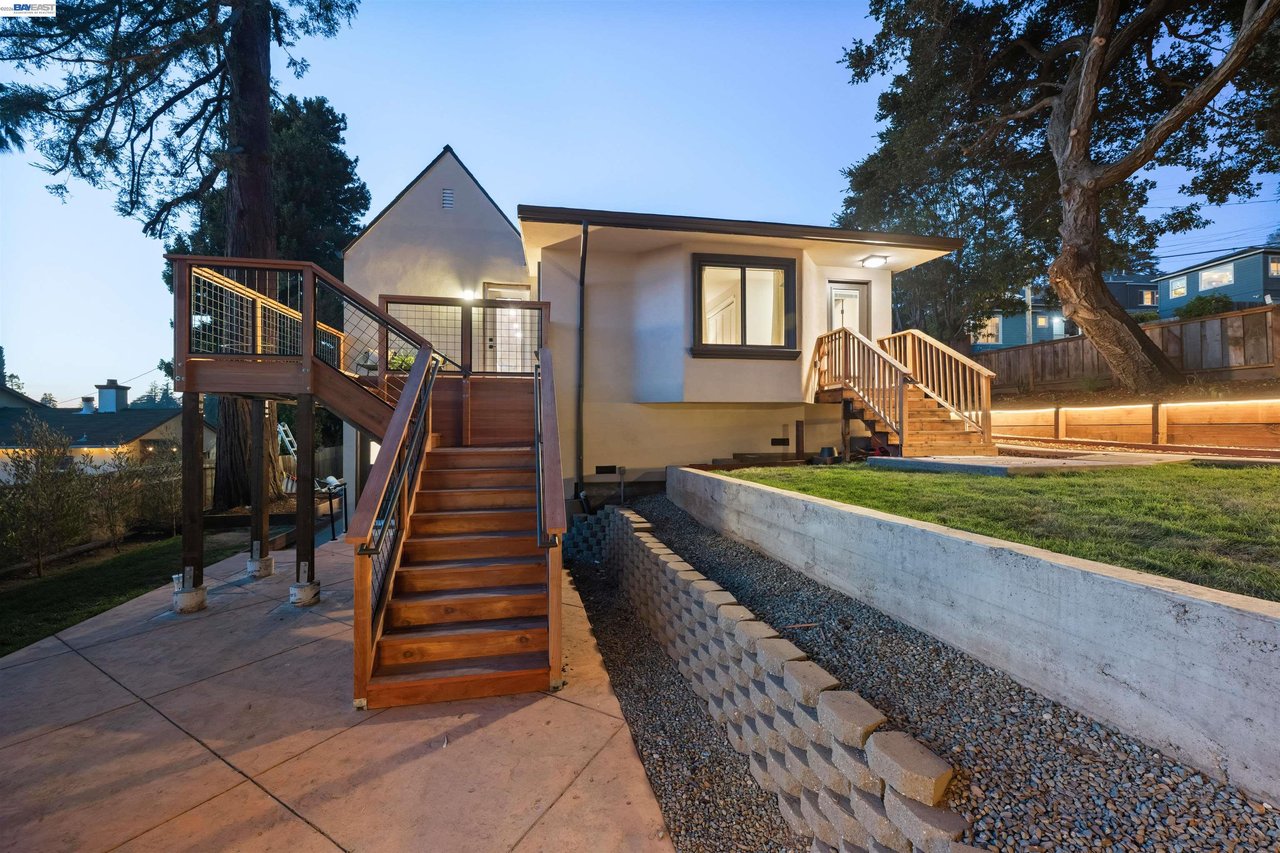Oakland home at dusk with broad wooden stairs, elevated decks, and a landscaped sloping yard.